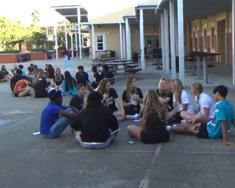 Atlantic Coast Mentors seated in small circles outside with their mentees.