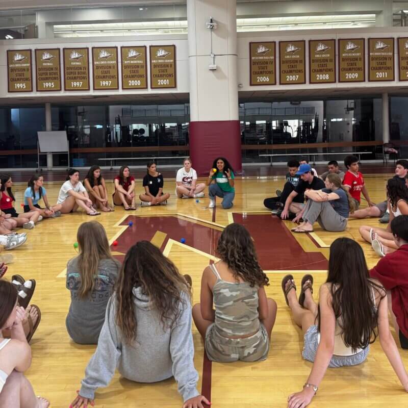 Newburyport and Georgetown High School mentors gather in a circle to debrief the activity.